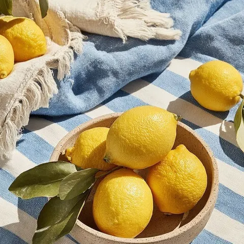 Lemons in a ceramic bowl on blue gingham