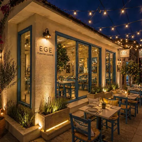 The taverna at night: string lights over blue chairs and set street-side tables